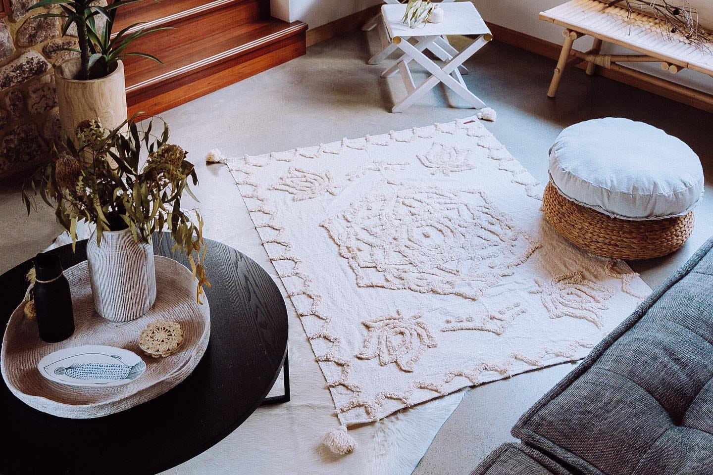 Living room with a textured rug, ottoman, and decorative items.