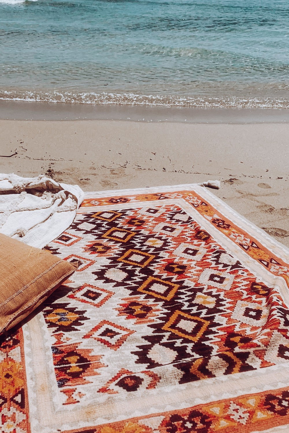Boho patterned throw blanket with geometric design styled on a sandy beach by the ocean
